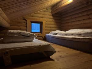 two beds in a log cabin with a window at The Log Cabin in Hadsund