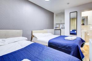 a room with two beds with blue and white sheets at Hampstead Residence Hotel in London