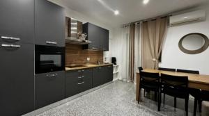 a kitchen with black cabinets and a table with chairs at Black Daisy in Bernalda
