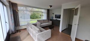 a living room with a couch and a chair and a window at Dunopark Bungalow in Oostkapelle