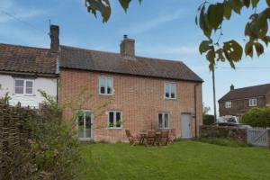 a brick house with tables and chairs in the yard at Harvey Cottage in Barney