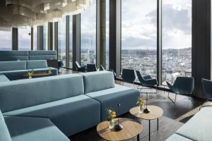 a waiting room with blue couches and tables and windows at ARCOTEL Tabakfabrik Linz in Linz