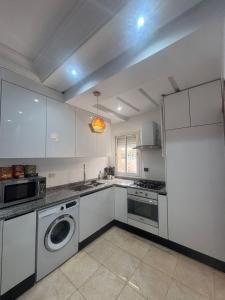 a kitchen with white cabinets and a washer at Sea View 1 Bedroom Apartment with 100m Terrace in Sousse