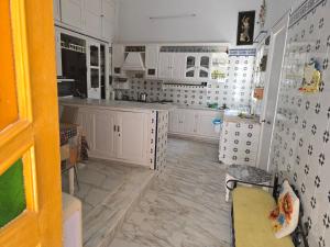 a kitchen with white cabinets and a tiled floor at Dar lel khedija in Mahdia