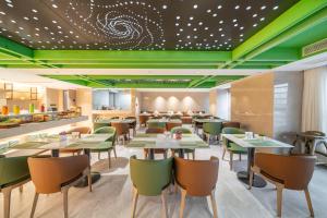 a restaurant with green ceilings and tables and chairs at Argyle Waifiden Hotel in Guangzhou