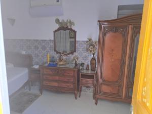 a bedroom with a wooden dresser and a mirror at Dar lel khedija in Mahdia