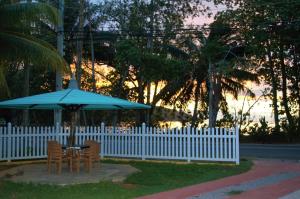 a table with a blue umbrella next to a white fence at 88 Days Self Catering Holidays & Accomodation in Baie Lazare Mahé