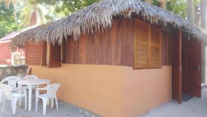 a building with a table and chairs and a thatch roof at Bungalow Soa Majunga in Mahajanga