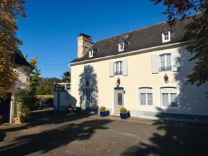 a white house with a chimney on a street at Maison Lasmarenx chambres d'hôtes in Jurançon