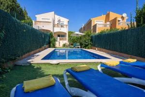 a villa with a swimming pool and two blue chairs at Villa El Olivo in Pollença