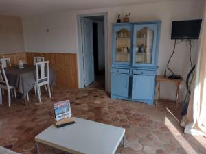 a living room with a blue cabinet and a table at Gîtes de beaux rêves, Glycine in Uxeau