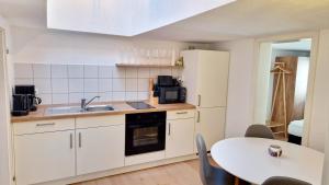 a kitchen with white cabinets and a table and a sink at ARGENTA Living - QUELLQUARTIER in Fulda