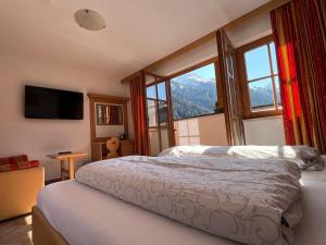 a bedroom with a bed and a large window at Hotel Garni Gafluna in Sankt Anton am Arlberg