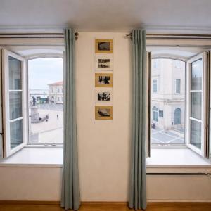 an empty room with two windows and pictures on the wall at Ellipse apartment in Piran +7 photos