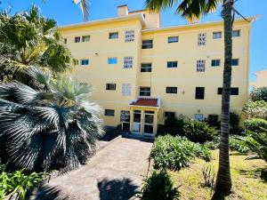 a large yellow building with palm trees in front of it at Santos Living Rentals in Funchal
