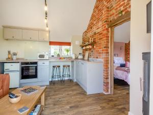 a kitchen with white cabinets and a brick wall at Alberts Dairy in Diss