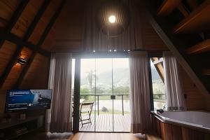 a living room with a large window and a balcony at Alabama Cabin - Serra Gaúcha in Picada Cafe