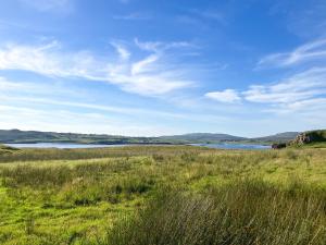 a field of grass with a lake in the background at Taigh Mullach Dearg in Portree +8 photos