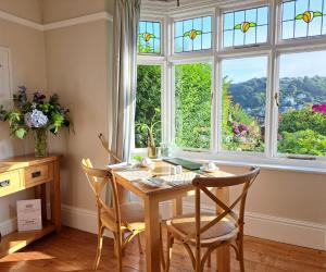 a dining room with a table and chairs and a window at Schooner Point Guest House in Looe