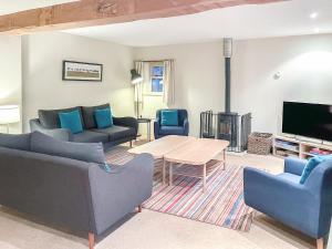 a living room with couches and a table and a tv at The Cart House in Helmsley
