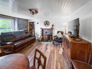 a living room with a leather couch and a fireplace at Croftbank in Lochranza