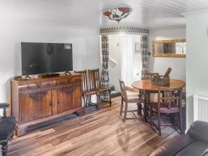 a living room with a table and a flat screen tv at Croftbank in Lochranza