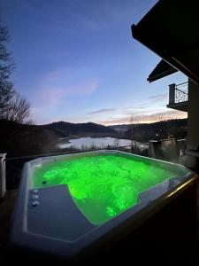 a green swimming pool with a view of a river at WołkoWilla - Willa z Jacuzzi na wyłączność MEGA WIDOK ! in Polańczyk +38 photos