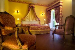 a bedroom with a bed with a canopy and a chair at Hôtel Château de Cavanac in Carcassonne