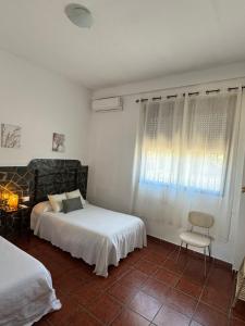 a bedroom with two beds and a chair and a window at Casa Rural La Aduana in Villanueva del Fresno +6 photos