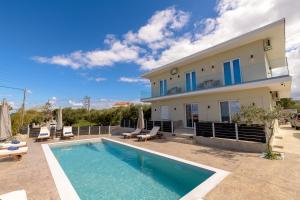 a villa with a swimming pool in front of a house at Athenia Apartments in Vasilikos