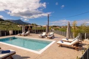 a pool with chaise lounge chairs and a swimming pool at Athenia Apartments in Vasilikos