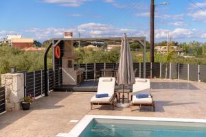 a patio with two chairs and an umbrella and a pool at Athenia Apartments in Vasilikos +91 photos