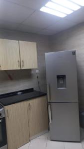 a kitchen with a white refrigerator and wooden cabinets at Oasis TOWER 1105 in Ajman  +19 photos