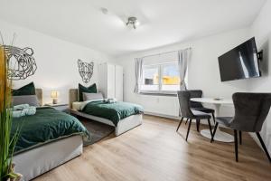 a bedroom with two beds and a desk and a table at Übernachtung an der A2 in Braunschweig