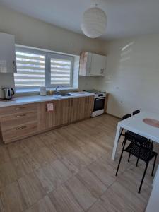 a kitchen with wooden cabinets and a table and a table and chairs at FB kotedžo apartamentai in Kretinga