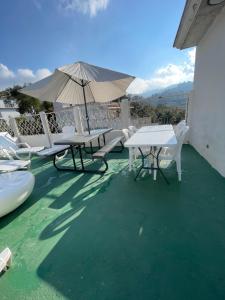 a patio with tables and chairs and an umbrella at Amazon Jade Hotel Boutique in San Bartolomé Milpas Altas