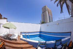 a swimming pool with a deck and a building at Aotea Backpacker Hostel in Iquique