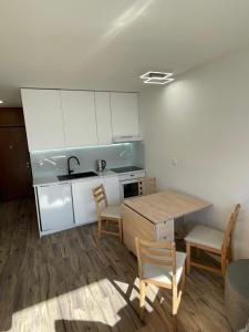 a kitchen with white cabinets and a table and chairs at Studio Pod Kaninom in Bovec