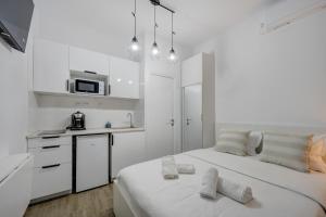 a white room with a bed and a kitchen at RHUM B07 - Old Town Courtyard in Bucharest