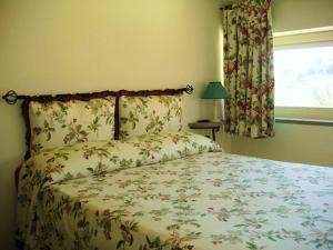 a bedroom with a bed with a floral bedspread and a window at Agriturismo Valle Siriaca in Castelnuovo di Porto