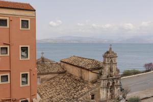 an old building with a clock tower next to the ocean at Mouragia by Kantoni in Corfu