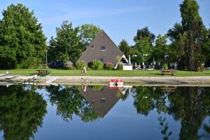 a reflection of a building in the water with benches at Camping Hunze Bulten in Annen