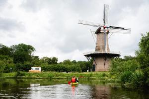 a woman in a kayak in front of a windmill at Camping Hunze Bulten in Annen