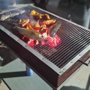 a grill with two fish and meat on it at Sofea Rania Homestay in Kota Belud