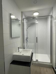 a white bathroom with a sink and a shower at Pier View 2 Bedroom Apartment in Herne Bay