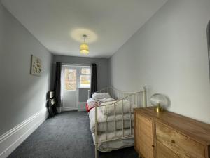 a bedroom with a bed and a chair and a window at Pier View 2 Bedroom Apartment in Herne Bay