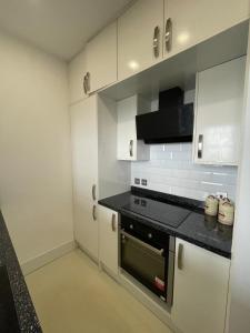 a kitchen with white cabinets and a black stove top oven at Pier View 2 Bedroom Apartment in Herne Bay +22 photos