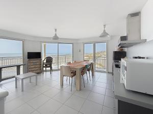 a kitchen with a table and a dining room with the ocean at Les Sables 4 in Fort-Mahon-Plage