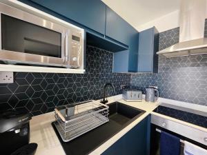 a kitchen with blue cabinets and a sink and a microwave at Bournemouth Luxury Apartment in Bournemouth