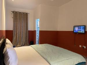 a bedroom with a bed and a tv on the wall at FE Purple Gold Hotel in Abuja